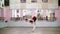 in dancing hall, Young ballerina in black leotard performs grand battement back, raises her leg up behind elegantly, in