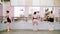 In dancing hall, Young ballerinas in black leotards perform pas soute, jumping near barre at mirror in ballet class.