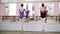 In dancing hall, young ballerinas in purple leotards perform developpe aside on pointe shoes, raise their legs up