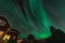 Dancing Northern lights Aurora borealis in autumn over backyard, part of house aside. Green Aurora high in sky. Umea town, Sweden