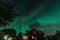 Dancing Northern lights Aurora borealis in autumn over wooden house, garden and garage. Umea town, Sweden, night