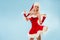 Dancing snow maiden. Charming and attractive blonde woman in a Santa suit.