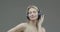 Dancing young beautiful girl in wireless headphones melomaniac listen to music enjoying sound, close up on gray backdrop