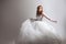 Dancing young woman in wedding dress. Charming bride on Light background with a shadow