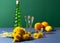 Dandelion Wine in vintage wineglasses. Modern still life with ingredients for preparation herbal mixture. Green bottle, two