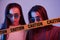 Danger, caution, yellow tape. Studio shot indoors with neon light. Photo of two beautiful twins