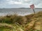 Danger collapsing dunes warning sign by ocean. Rosses point beach, county Sligo, Ireland.