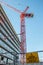 Danger construction site keep out sign with red crane over city