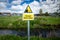 Danger Deep Water warning sign on rural river bank. Risk of drowning.