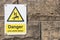 Danger Live Wires Below Warning Sign on a stone brick wall