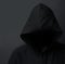 Danger lurking in the dark. an unidentifiable hooded man posing against a dark background.