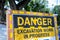 Danger roadsign with yellow and black colors. Stop sign closeup on summer background. Rustic wooden road sign