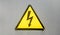 Danger sign of high voltage electricity. Yellow triangular sign with a lightning in the center. This warning is written on an old