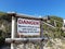 Danger sign says Beware of freak waves and watch your footing on the island Robberg Beach, people walking up path