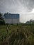 Danger signboard at the field viewing the electric transmission tower at the isolated field