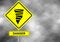 Danger tornado road sign . Yellow hazard warning sign against grey sky