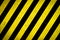 Danger zone: Warning sign yellow and black stripes painted over concrete wall coarse facade with holes and imperfections texture
