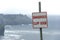 Dangerous cliff edge sign in overcast weather at Cliffs of Moher in Ireland. Danger sign warning.