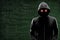 Dangerous hacker over abstract digital background with binary code. Obscured dark face in mask and hood. Data thief