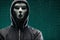 Dangerous hacker over abstract digital background with binary code. Obscured dark face in mask and hood. Data thief