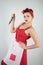 Dangerous pin up girl housewife in red vintage polka dot dress stands with a huge kitchen knife in her hands and angrily rejoices