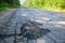 Dangerous pothole in the asphalt rural road. Road damage