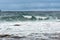 Dangerous sea wave crashes on a rocky coastline with splashes and foam before a storm in the Barents