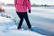 Dangerous thin ice. Woman takes risk to step on frozen river surface in winter. Caution, unsafe water, drop possibility