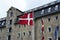 Danish flag waving with the Admiral Hotel on the background, Copenhagen, Denmark