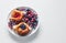 Danish with raspberries and blueberries on  round plate with berries on  white table