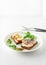 Danish smorrebrod open sandwiches on white plate, fork and knife, green salad leaves on white background, closeup view