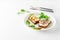 Danish smorrebrod open sandwiches on white plate, fork and knife, green salad leaves on white background with copy space