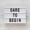 `Dare to begin` words on a modern board on a white wooden background, top view. Overhead, from above, flat lay