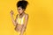 Daring african teen girl peel banana isolated on summer yellow background