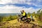 A daring motorcyclist on the top of the high Ural mountain sugomak is ready to go down on a summer sunny day