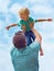 Daring to dream. A father swinging his toddler son in the air against a sky background.