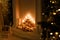 Dark aesthetic close up shot of decorative fireplace with wood, candles and shiny garland lights bokeh, fir branches. Merry