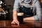 Dark beer with foam in glass from bartender. Guy gives drink on wooden counter