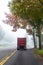 Dark big rig classic semi truck with high pipes turning on the autumn road with fog