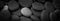 Dark black abstract smooth round pebbles sea texture background