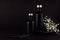 Dark black minimalist interior with blank black bottles, white small flowers on dark wood board, mock up.