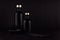 Dark black minimalist interior. Blank black cosmetics bottles on dark wood board with copy space.