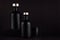 Dark black minimalist interior. Blank black cosmetics bottles on dark wood board, mock up.