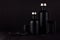 Dark black minimalist interior. Blank black cosmetics bottles on dark wood board, mock up.