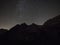 Dark black night sky panorama with stars milkyway over alpine mountain peaks summit hill in Ehrwald Tyrol Austria alps
