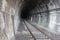 Dark black shaded tunnel in an underground tunnel in a cavern of a railway along the tracks of a train towards the station