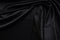 Dark black silky, satin fabric, wave, draperies. Beautiful textile backdrop. Close-up. Top view