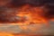 Dark blood red sky background. Dramatic heavy clouds with the hint of the sun at sunset. Many orange tones and patterns of clouds