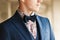 Dark blue bow tie with flowers shirt and suit on men\'s neck.