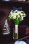 Dark blue bow tie on a luxury bridal bouquet of white flowers on a shelf